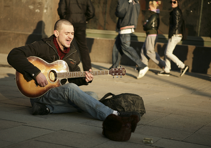 Уличный музыкант играет на гитаре